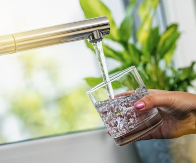 woman hand holds a glass to Filing it with water from tap
